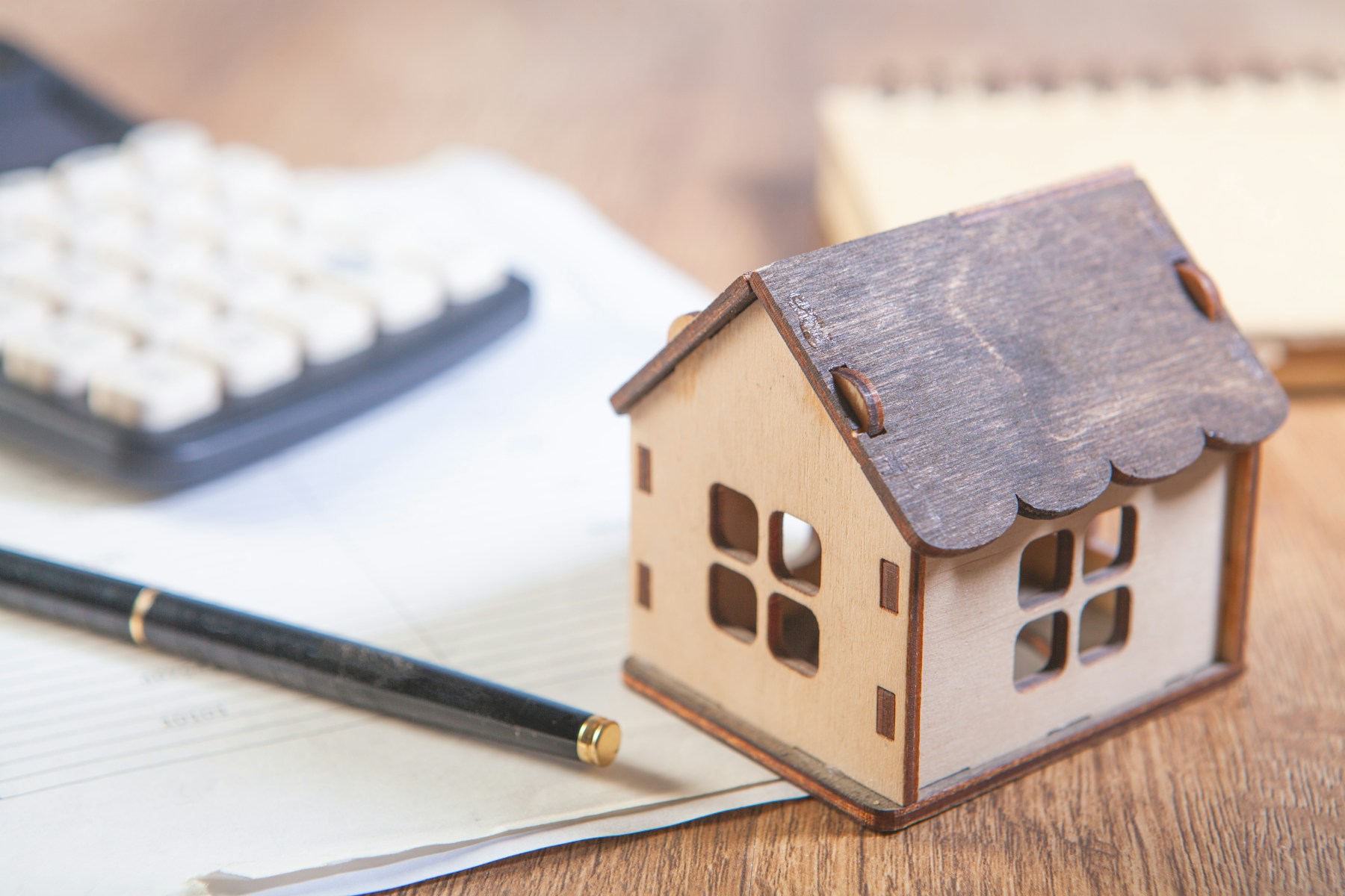Hausmodell, Stift und Rechner für einen Überblick zur Immobilienfinanzierung