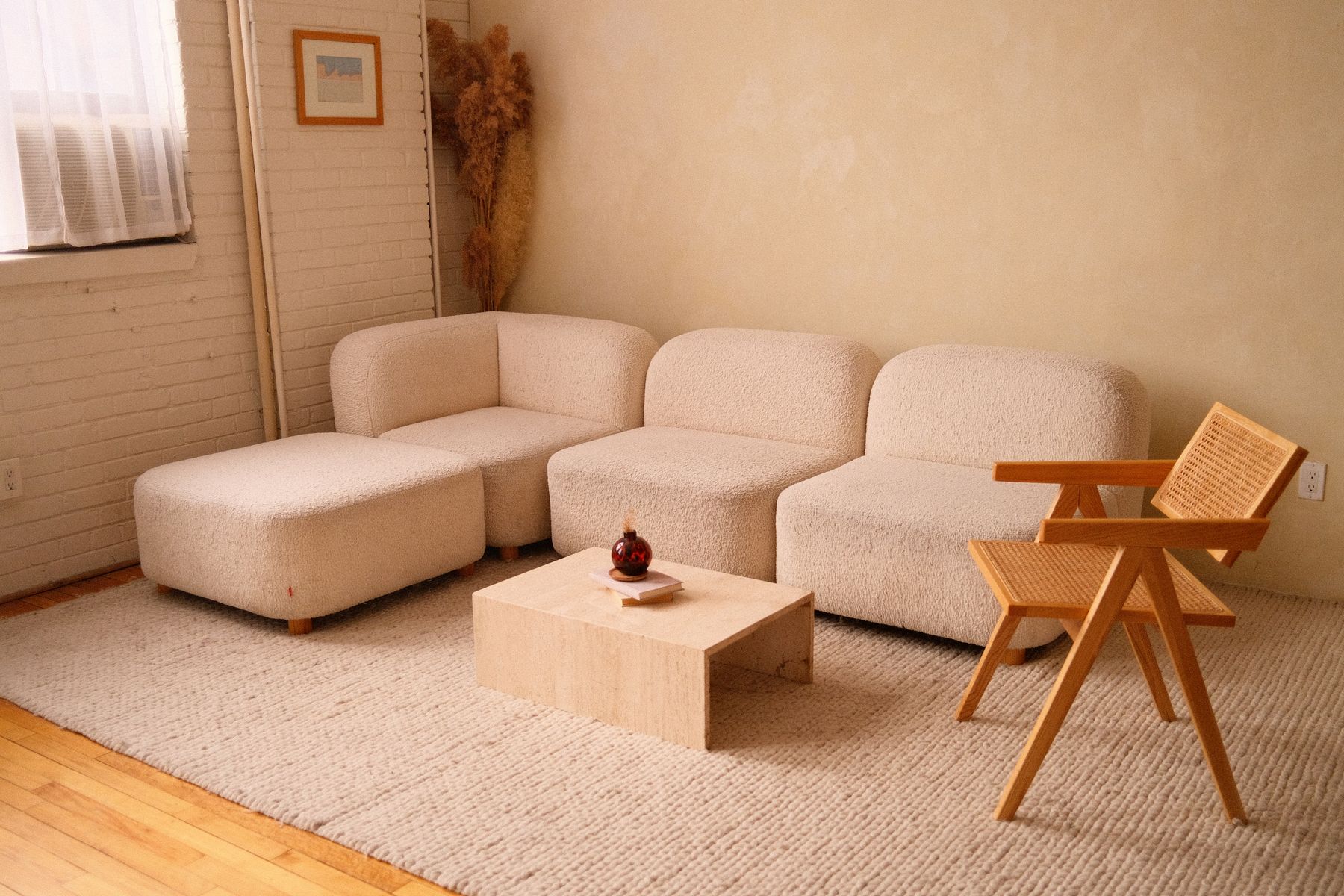 Beiges Sofa und Holzsessel in einem warmen, hellen Wohnraum